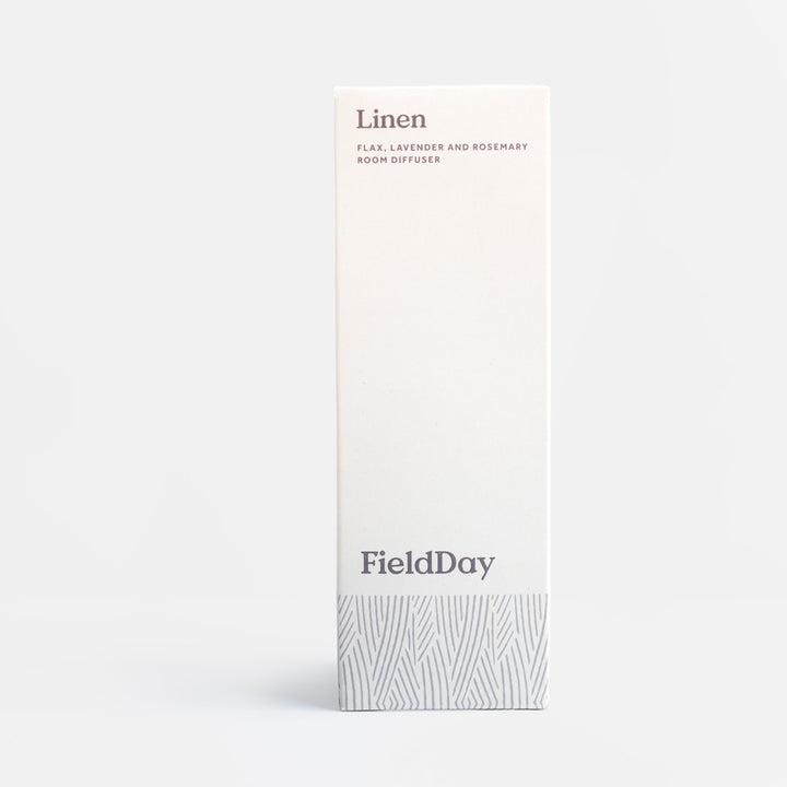 A tall, narrow white box for a FieldDay linen room diffuser, featuring minimalist gray text and a subtle gray patterned band at the bottom, set against a clean light gray background.
