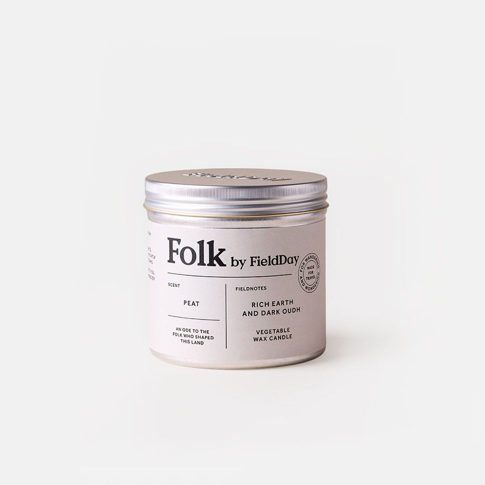 A silver metal tin candle with a white label reading 'Folk by FieldDay' and 'Peat', photographed on a clean white background.