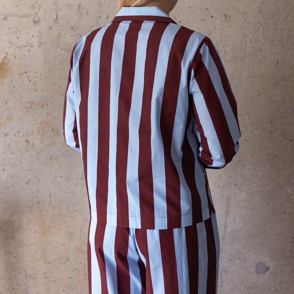 Back view of a woman in a blue and wine striped pyjama shirt and trousers