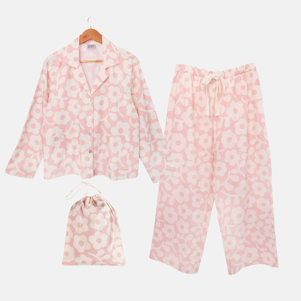 Pale pink pyjama shirt and wide-leg trousers with a large cream flower print, shown with a matching drawstring bag