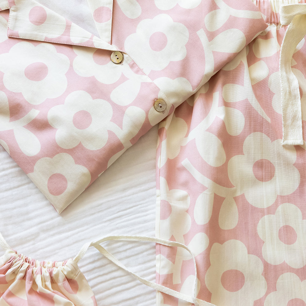 Pale pink pyjama shirt and wide-leg trousers with a large cream flower print, shown with a matching drawstring bag