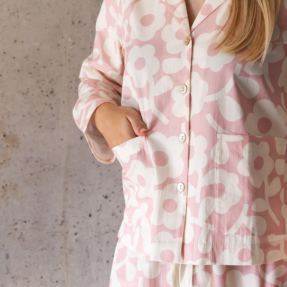 Close-up of a pink and cream floral pyjama shirt with pearly buttons and a hand in the front pocket