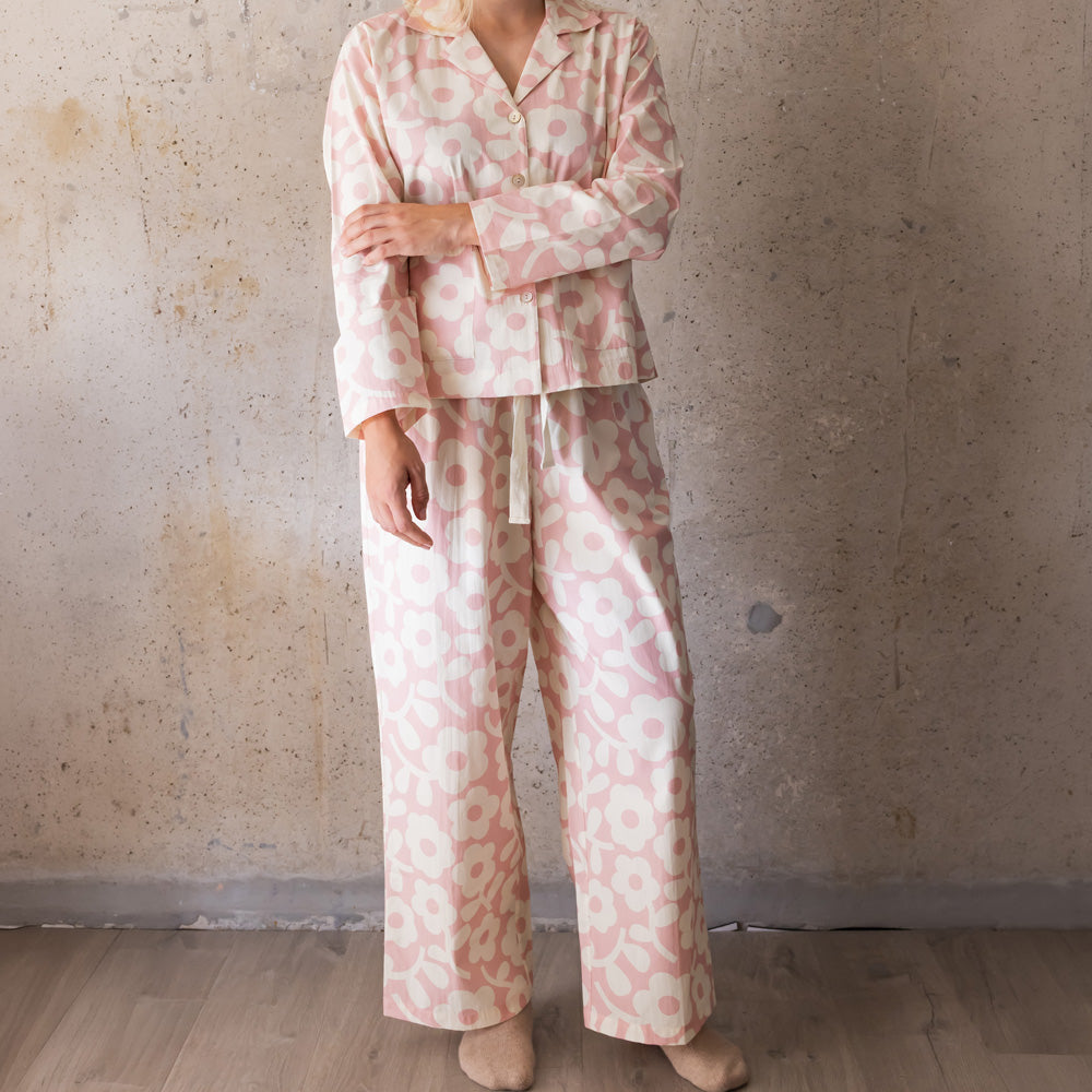 Woman wearing a pale pink and cream flower print long pyjama set with wide-leg trousers