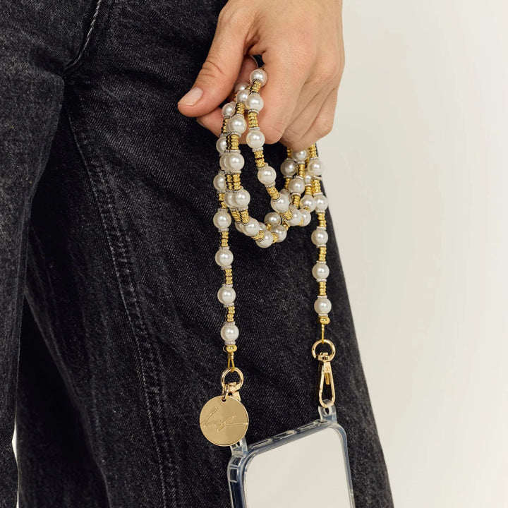 Hand holding a pearl and gold phone chain attached to a clear phone case