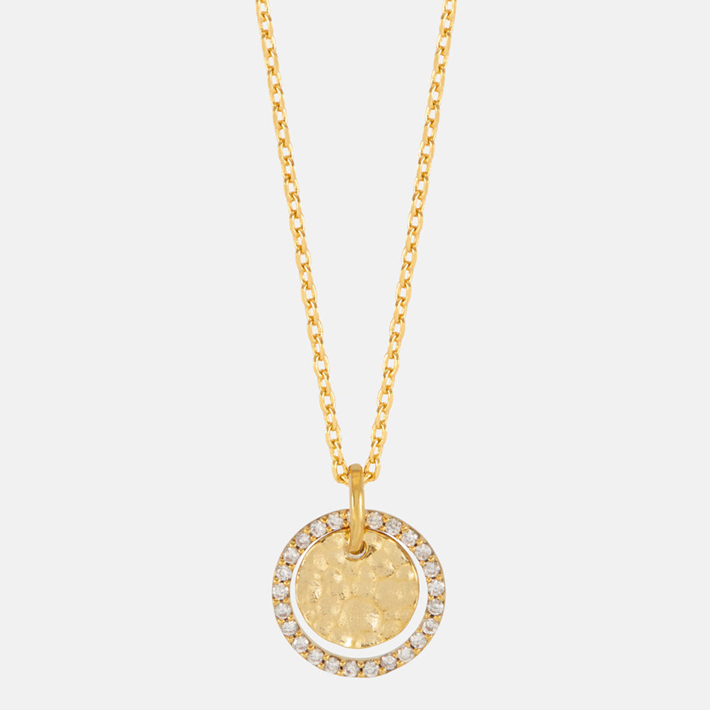 Close-up of a hammered gold coin pendant framed with sparkling stones
