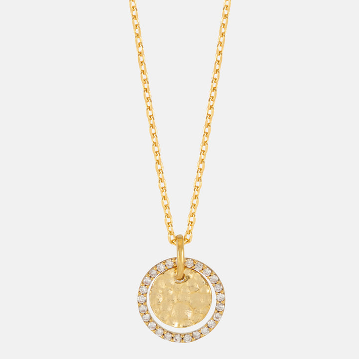 Close-up of a hammered gold coin pendant framed with sparkling stones