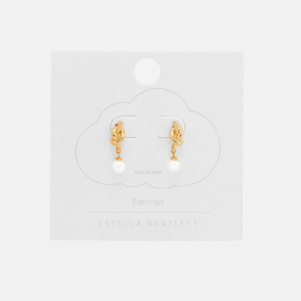 Pair of gold knot stud earrings with round white pearl drops, on a white cloud-shaped earring card