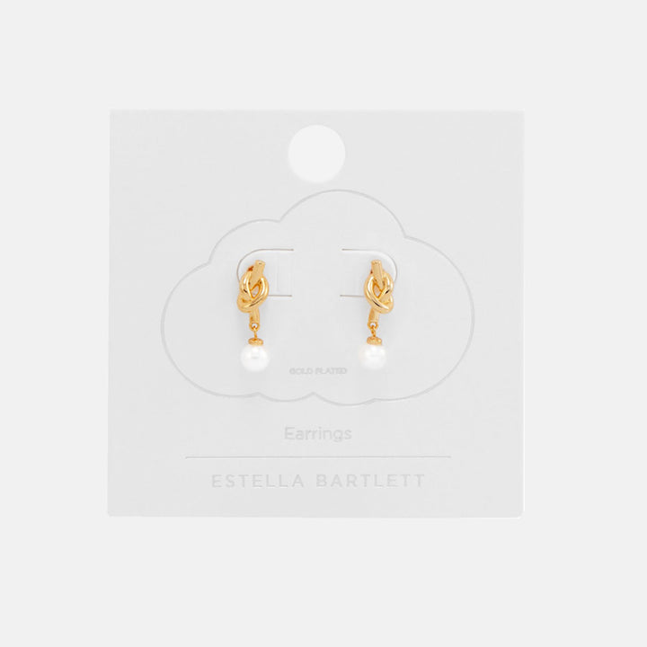 Pair of gold knot stud earrings with round white pearl drops, on a white cloud-shaped earring card
