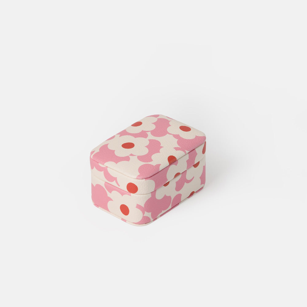 A small rectangular jewellery box with rounded corners, featuring a pink and off-white floral pattern with red centers, set against a plain light gray background.