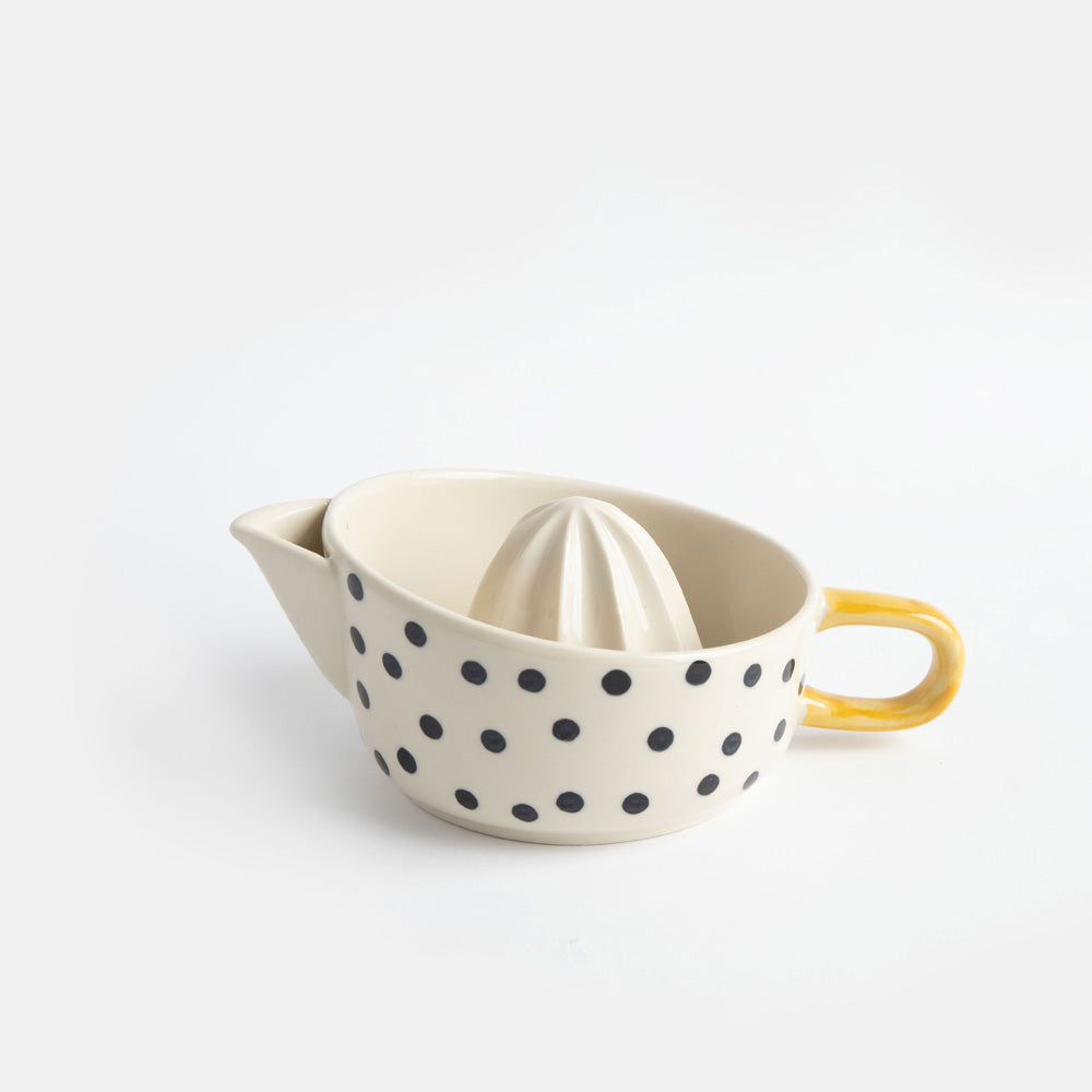 hand painted ceramic citrus squeezer with a small black dots design and mustard handle