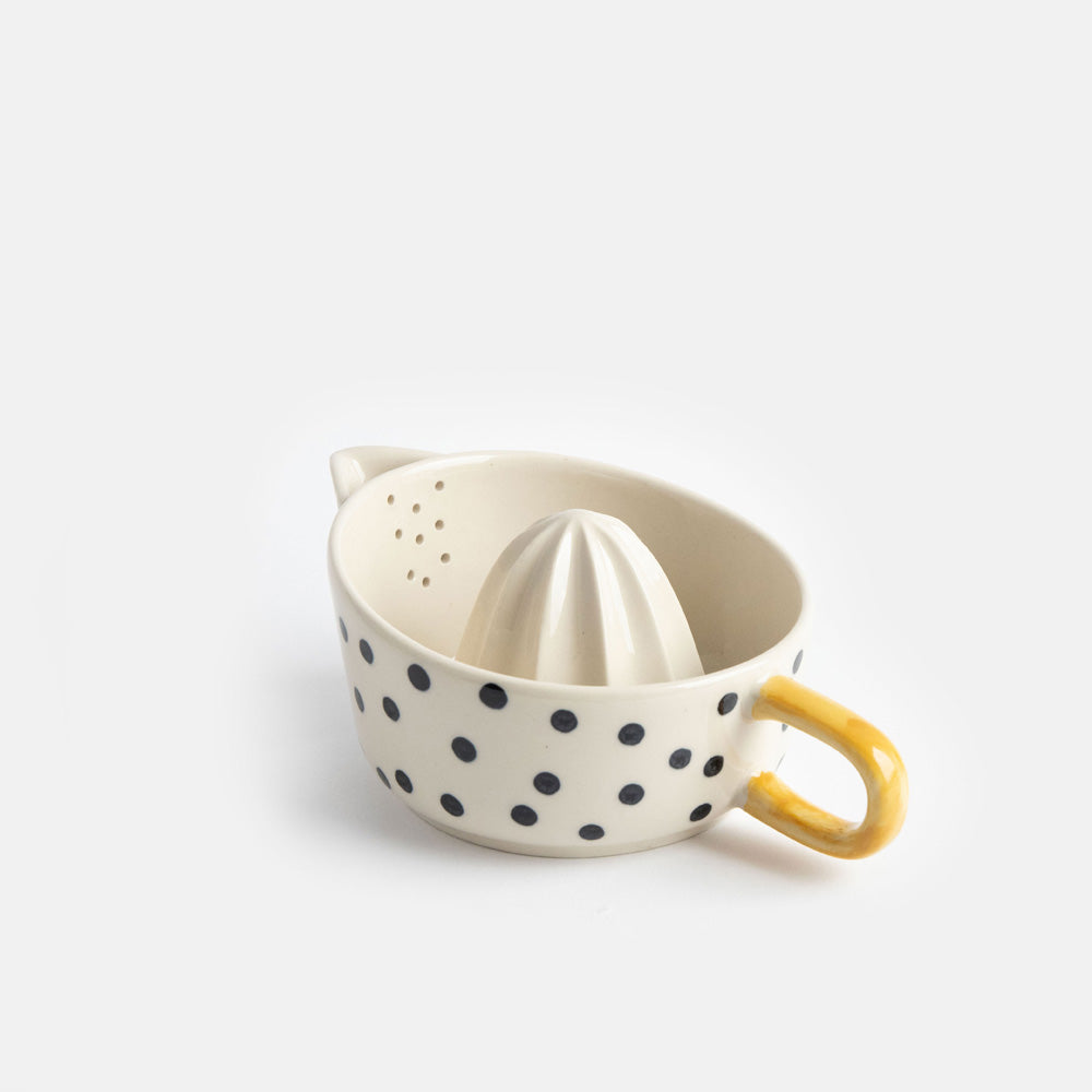 hand painted ceramic citrus squeezer with a small black dots design and mustard handle