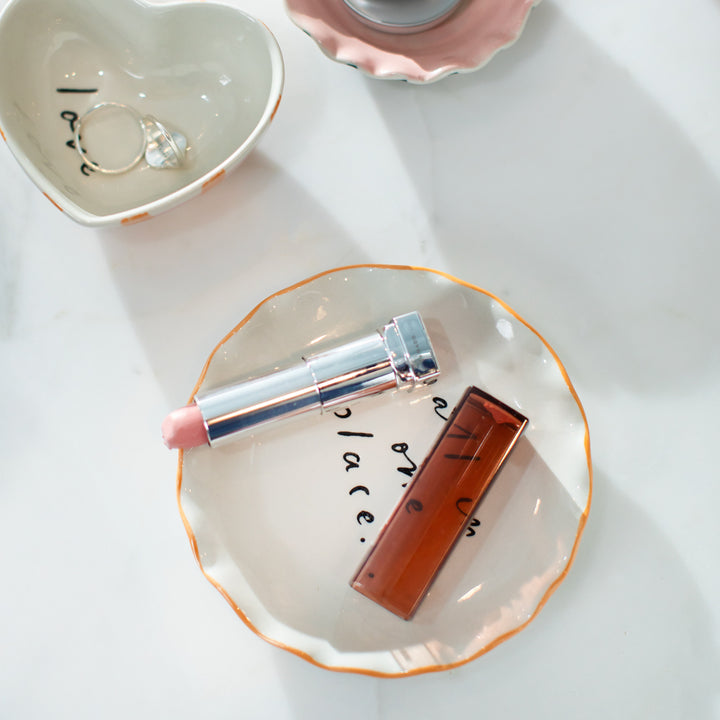 scalloped edge trinket dish with lipstick on, on a white background