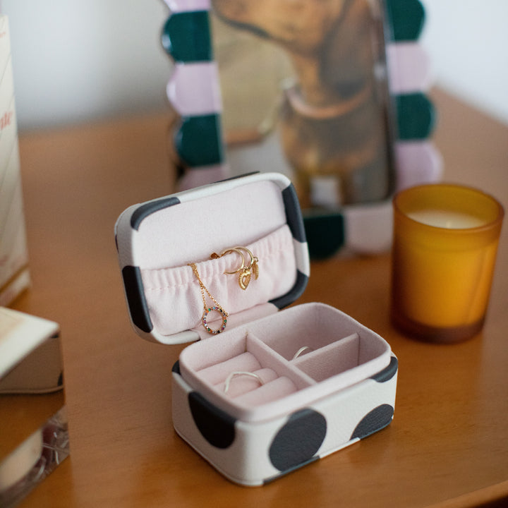 black & white spot small jewellery box with necklace and earrings inside on a wooden surface