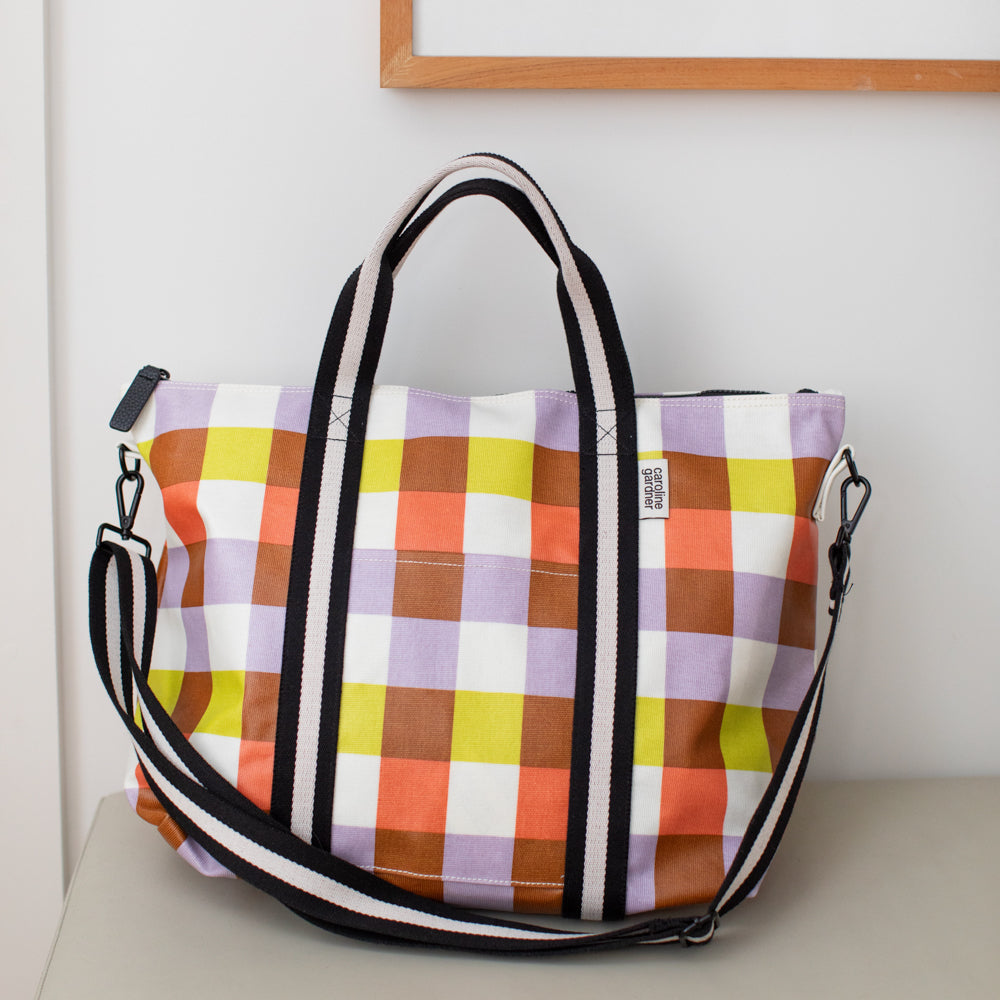 colourful checked weekend bag with black & white webbing handles and shoulder straps