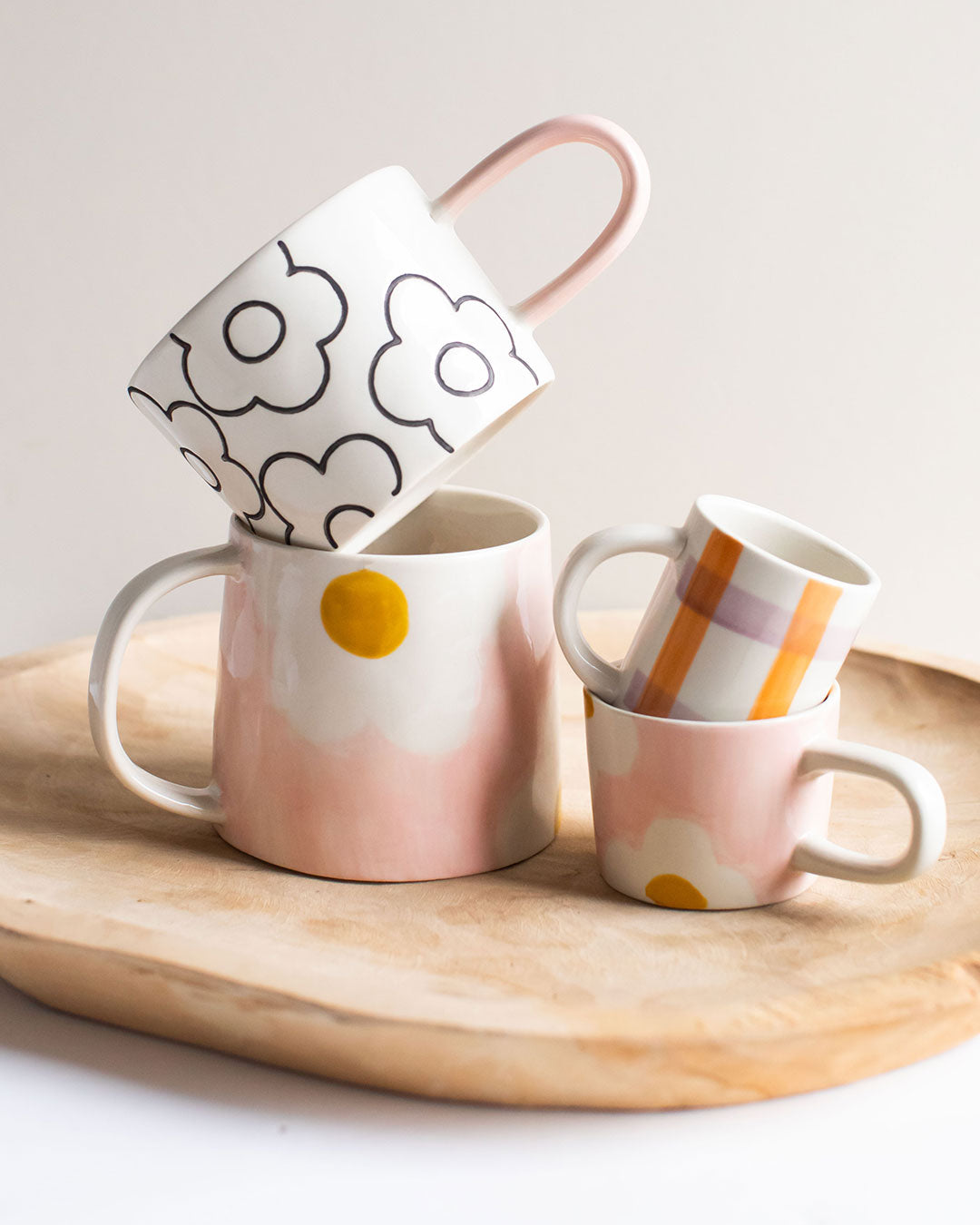 4 mugs and espresso cups stacked on a wooden board