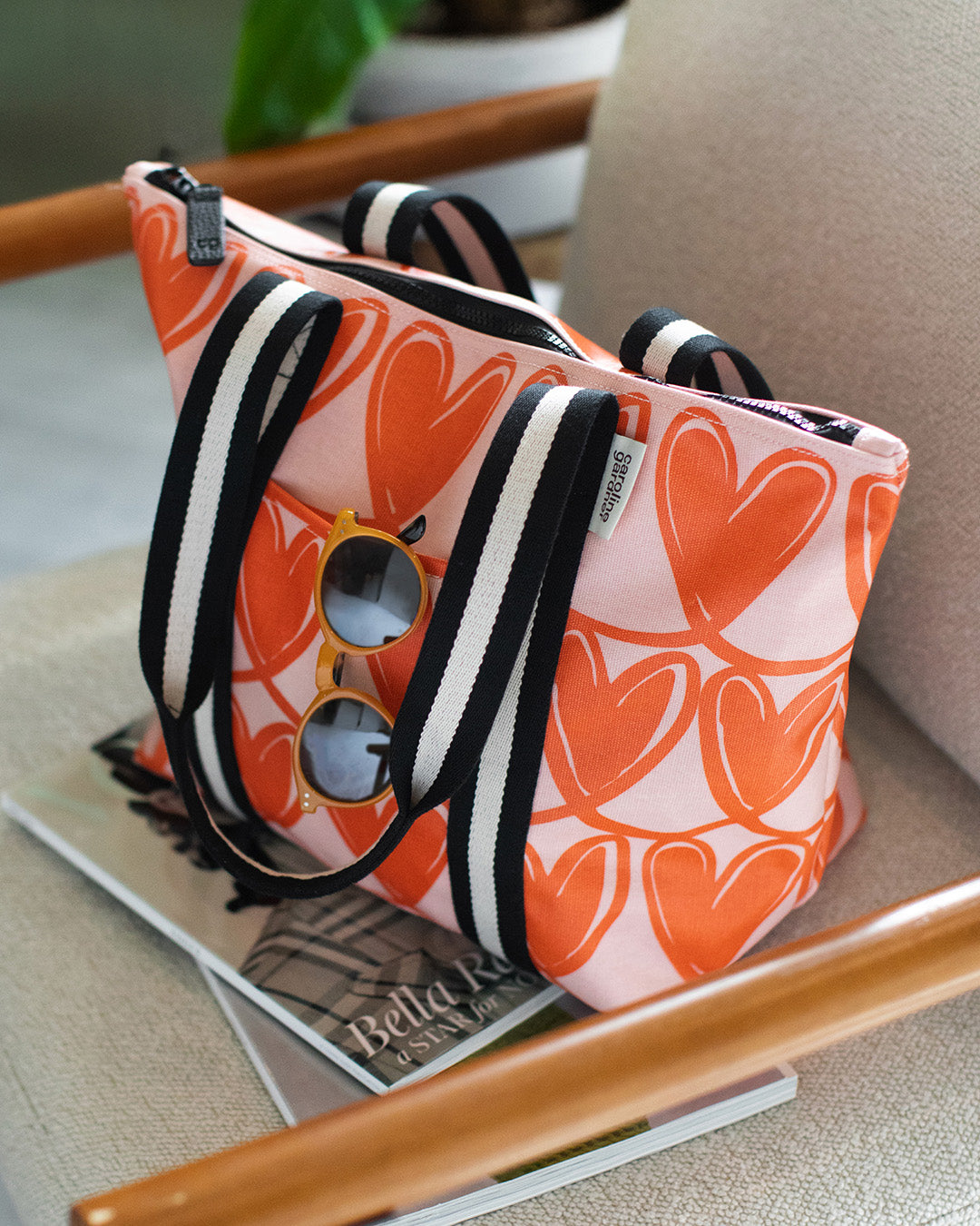 women's weekend bag with red heart print on pink base, on a chair