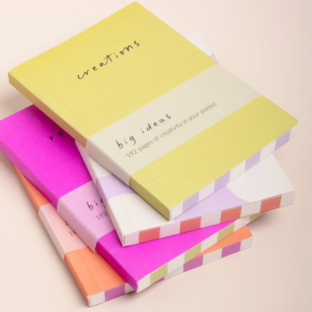 stack of 4 colourful notebooks on a light grey background
