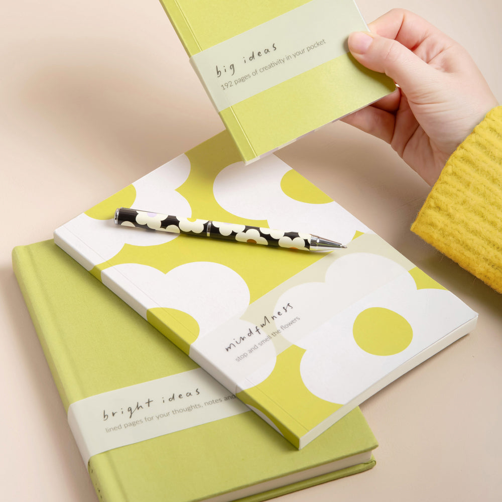 3 green notebooks, one with a floral design, and a black and white flower print pen