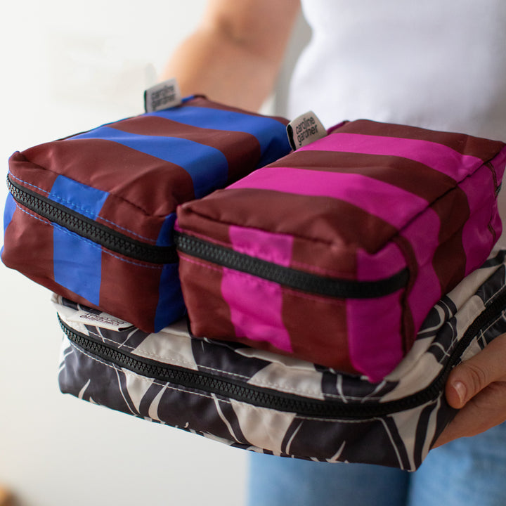 person holding a set of 3 packing cubes in colourful stripe & heart designs