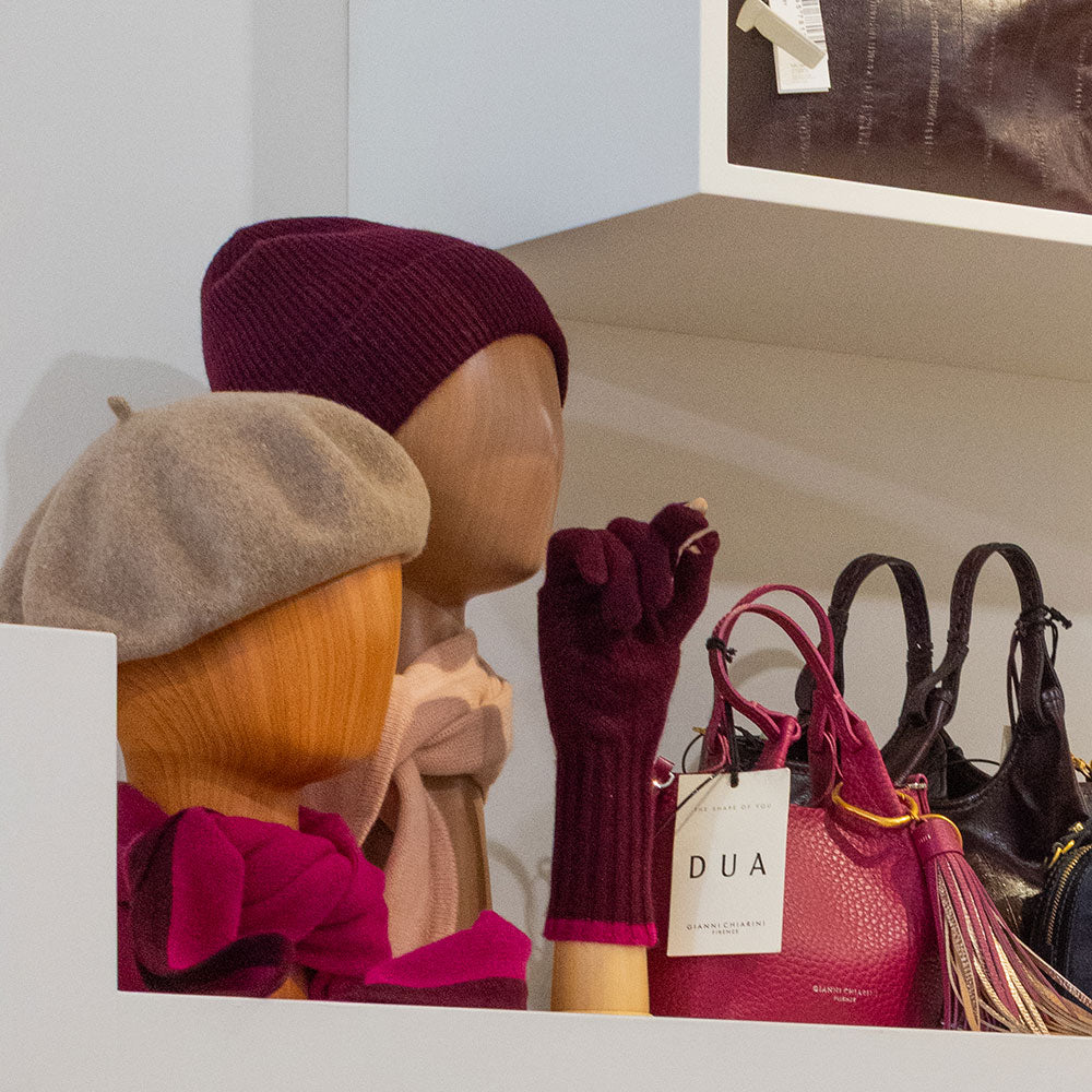 a shop shelf display showing hats and gloves on mannequin heads and hands and leather bags
