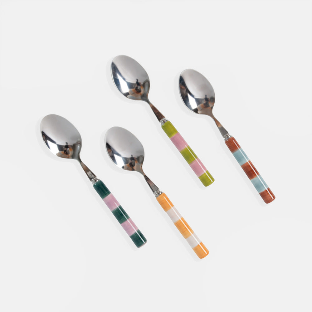 Four decorative spoons with polished silver metal heads and colorful striped handles, arranged diagonally on a light gray background.
