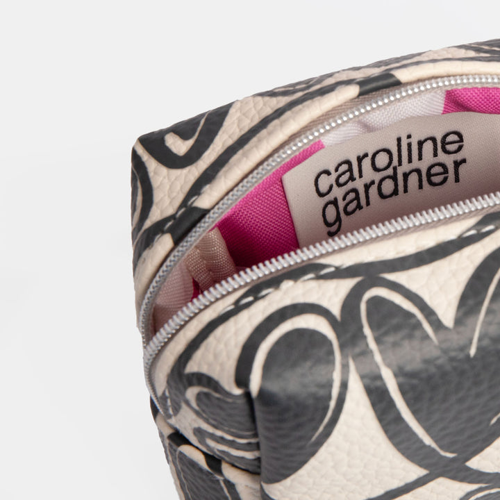 Cosmetic bag with black looped hearts pattern and pink ribbon on a white background