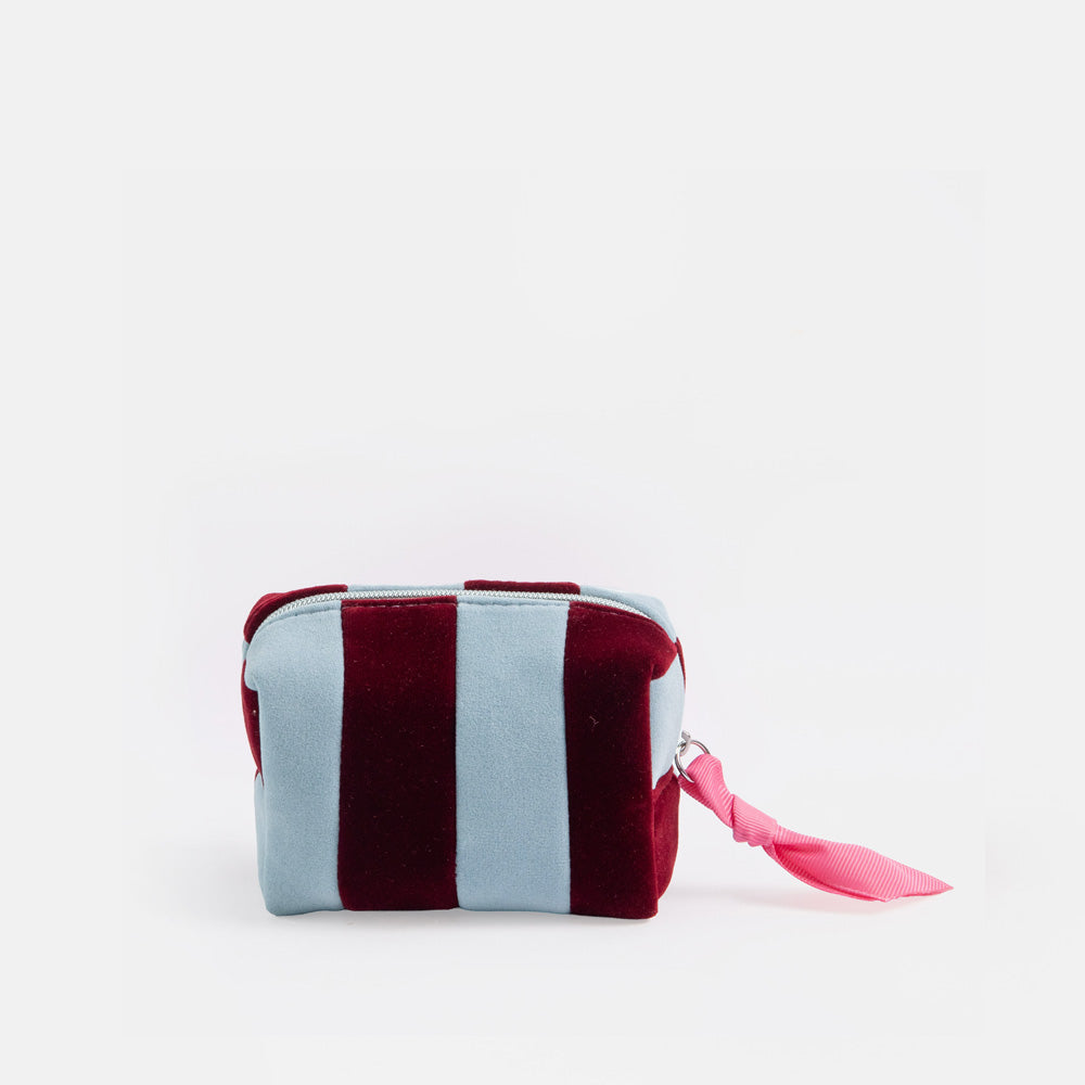 A small zippered cosmetic pouch with alternating vertical stripes of dusty light blue and deep burgundy velvet, featuring a bright pink ribbon pull on a white background.
