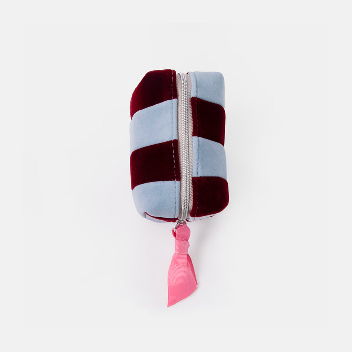 A small zippered cosmetic pouch with alternating vertical stripes of dusty light blue and deep burgundy velvet, featuring a bright pink ribbon pull on a white background.