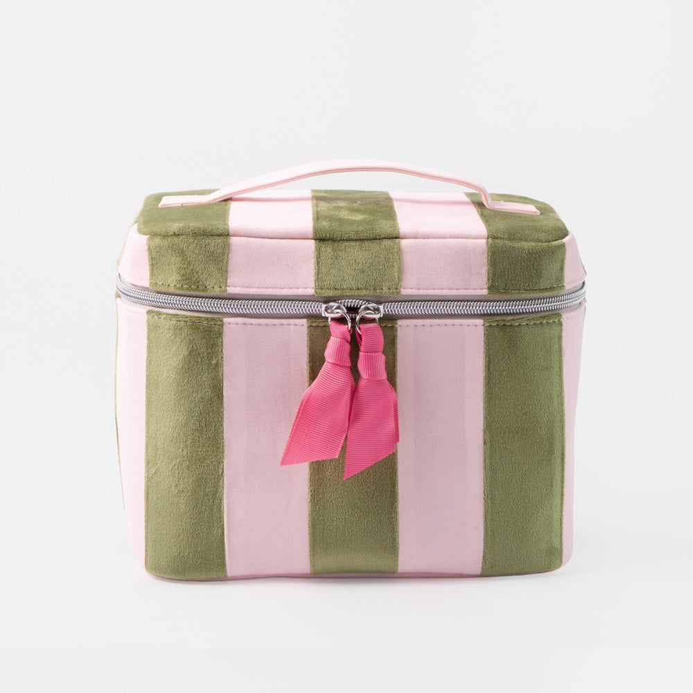 A square zippered vanity case with vertical pink and olive green stripes, featuring a light pink top handle and a pink tassel charm on the zipper.