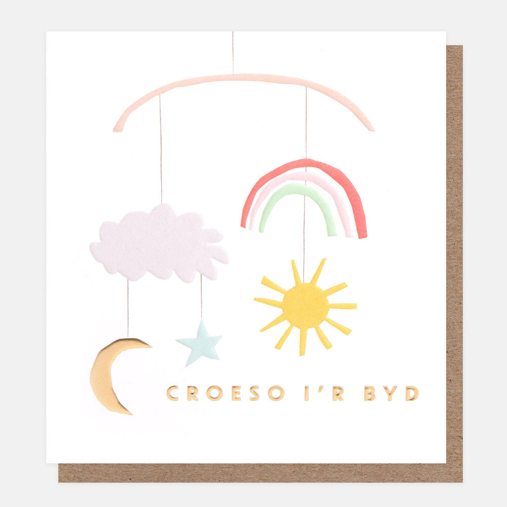 welsh language new baby baby card featuring a mobile with a rainbow, sun, moon & star and the text croeso i'r byd