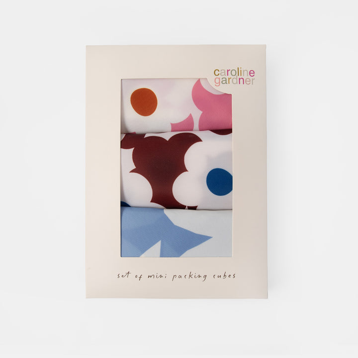 Caroline Gardner set of mini packing cubes in a cream-colored cardboard box with a clear window showing three colorful patterned cubes.