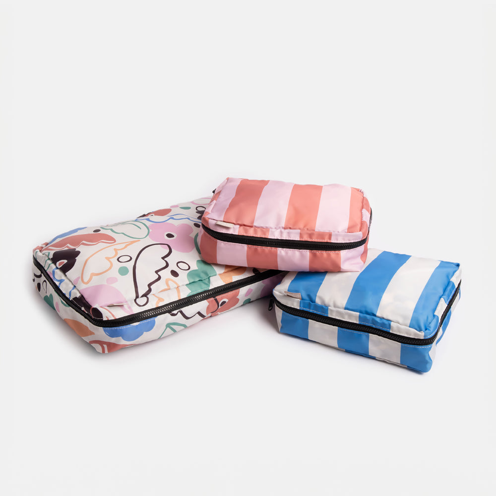 set of 3 packing cubes. 1 large win abstract floral design and 2 smaller cubes in blue and pink candy stripes