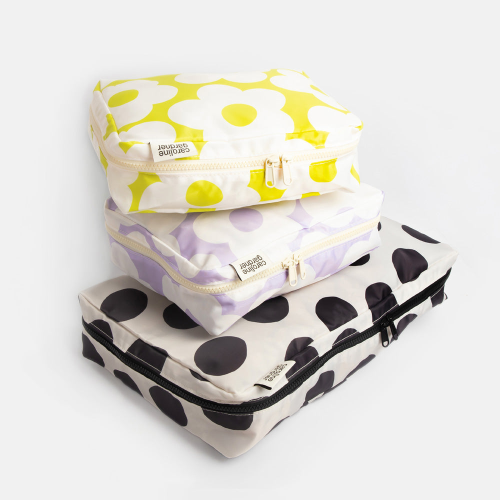 Set of three patterned packing cubes stacked on a white background