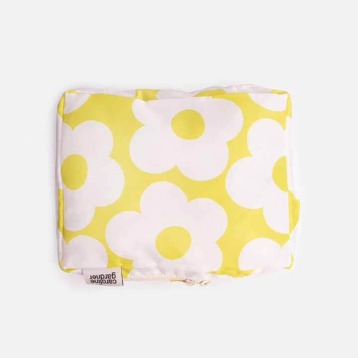 Yellow and white floral patterned packing cube with a 'caroline gardner' brand label on a white background
