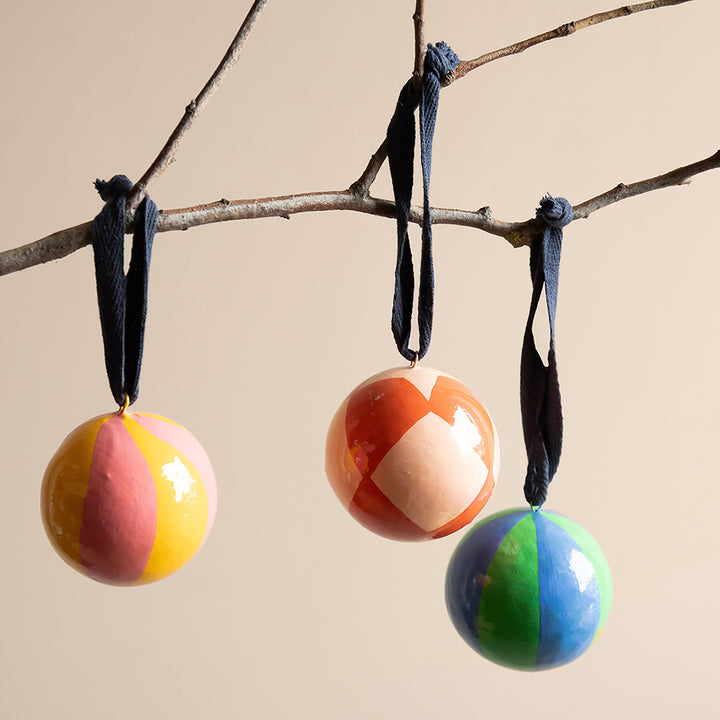 3 colourful Christmas baubles hanging from a branch