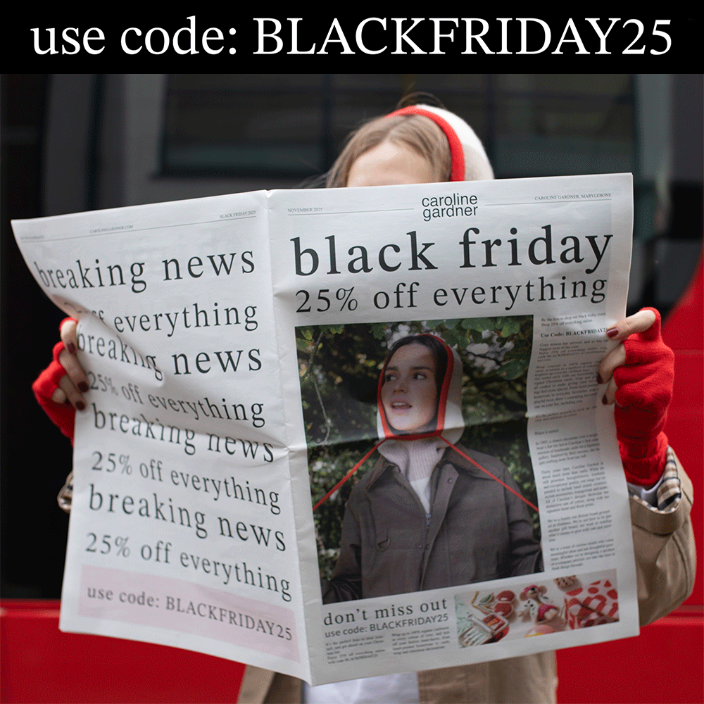 woman holding a newspaper while a red london bus drives past in the background