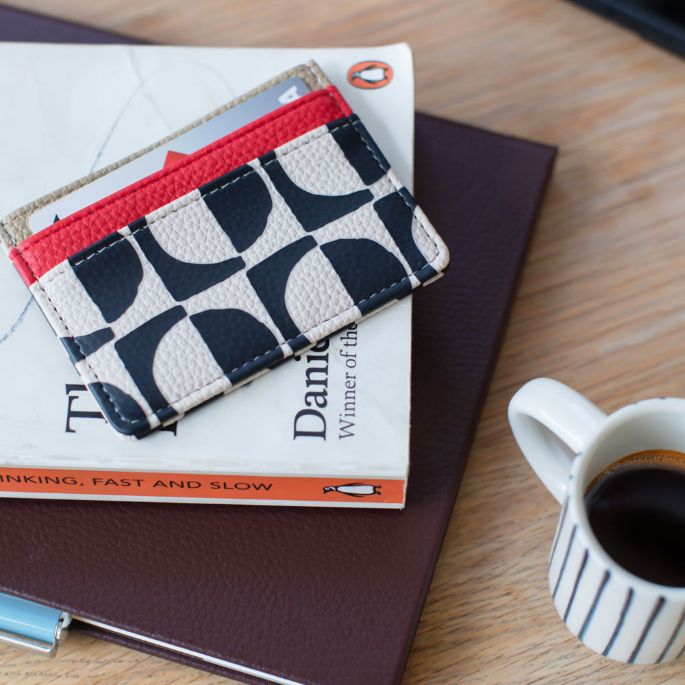 Patterned cardholder wallet on a book with a cup of coffee on a wooden surface