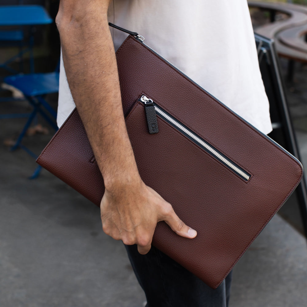 Person holding a purple laptop sleeve outdoors