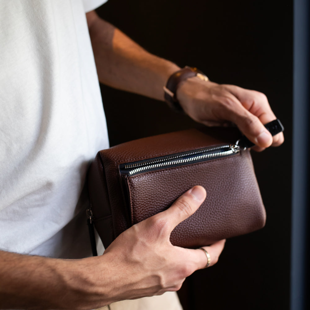 Person holding a purple small wash bag with a dark background