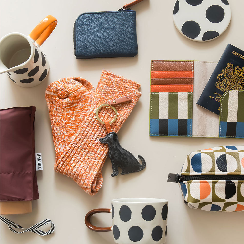 Collection of gift items including a mug, wallet, passport holder, and socks on a light surface.