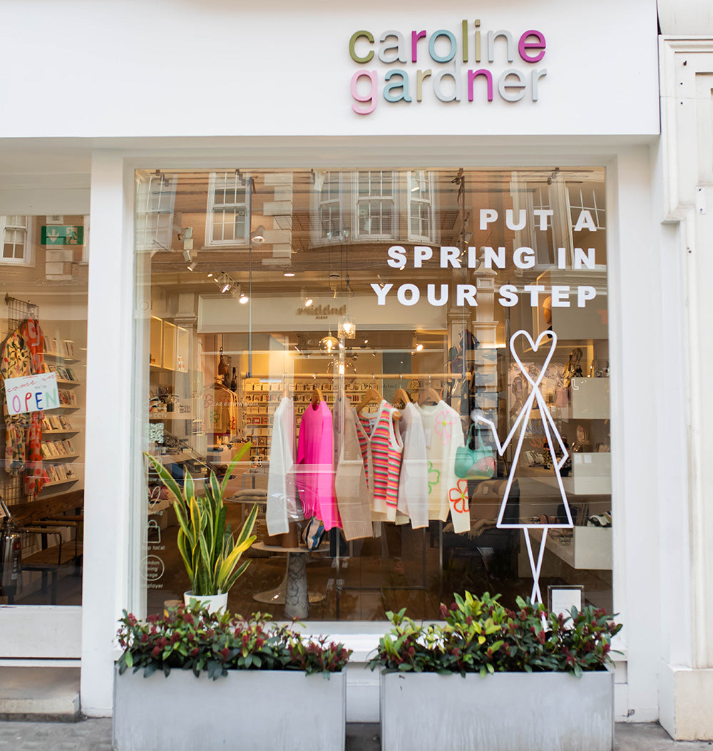 Storefront with 'caroline gardner' branding and window display of clothing.