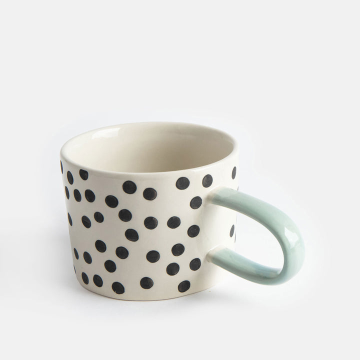 hand painted ceramic stoneware mug with small black dots design and a light blue elongated handle