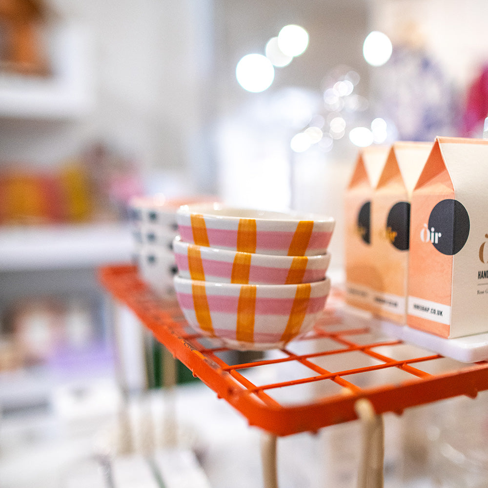 Stack of colorful bowls on an orange metal shelf with a blurred background