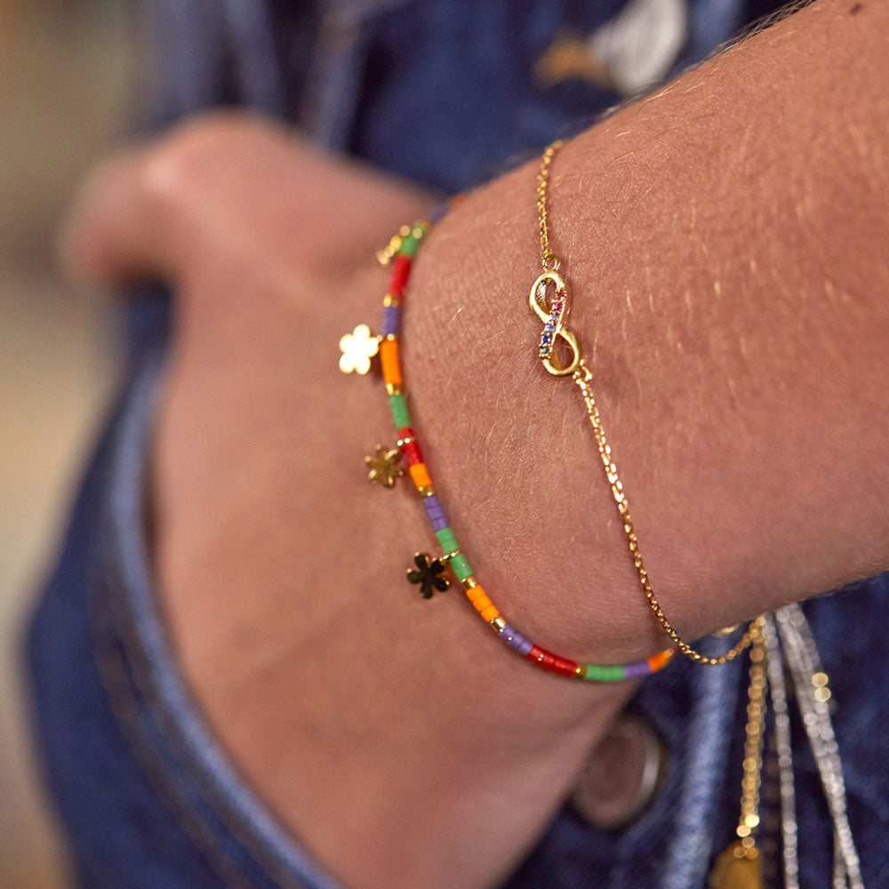 multi-coloured beaded bracelet with gold ditsy flower charms worn with gold link bracelet