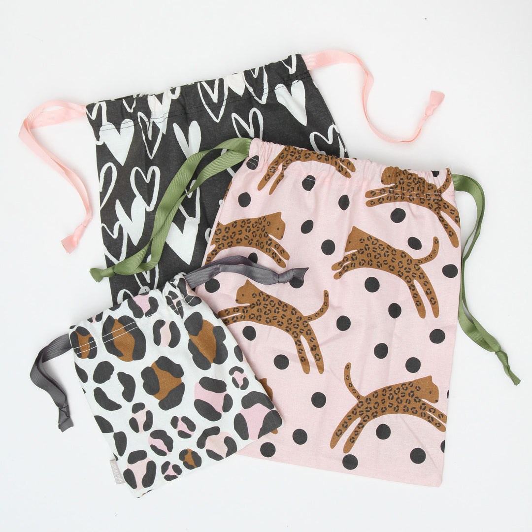 Three canvas drawstring bags in three different sizes and prints